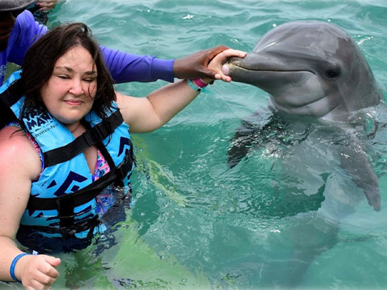 Smiling woman petting a dolphin